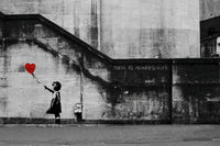 a black and white photo of a girl holding a red heart balloon