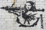 a brick wall with a painting of a woman holding a gun