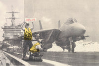 a man holding a sign next to a fighter jet