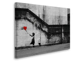 a black and white photo of a girl holding a red heart balloon