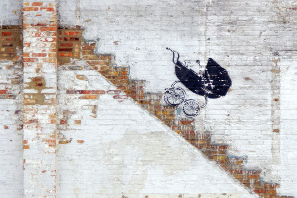 a painting of a baby carriage on a brick wall