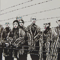 a group of people standing behind a barbed wire fence