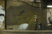 a man spray painting a wall with animals on it